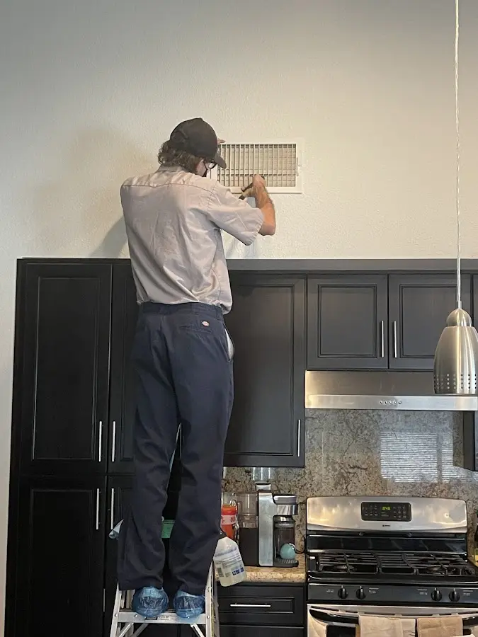 Technician inspecting an air vent during HVAC service in Flatwoods